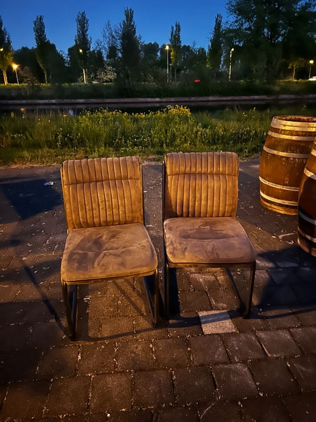 2 stoelen, 2 houten tonnen als plantenbak gebruikt en een lage (tv?)kast