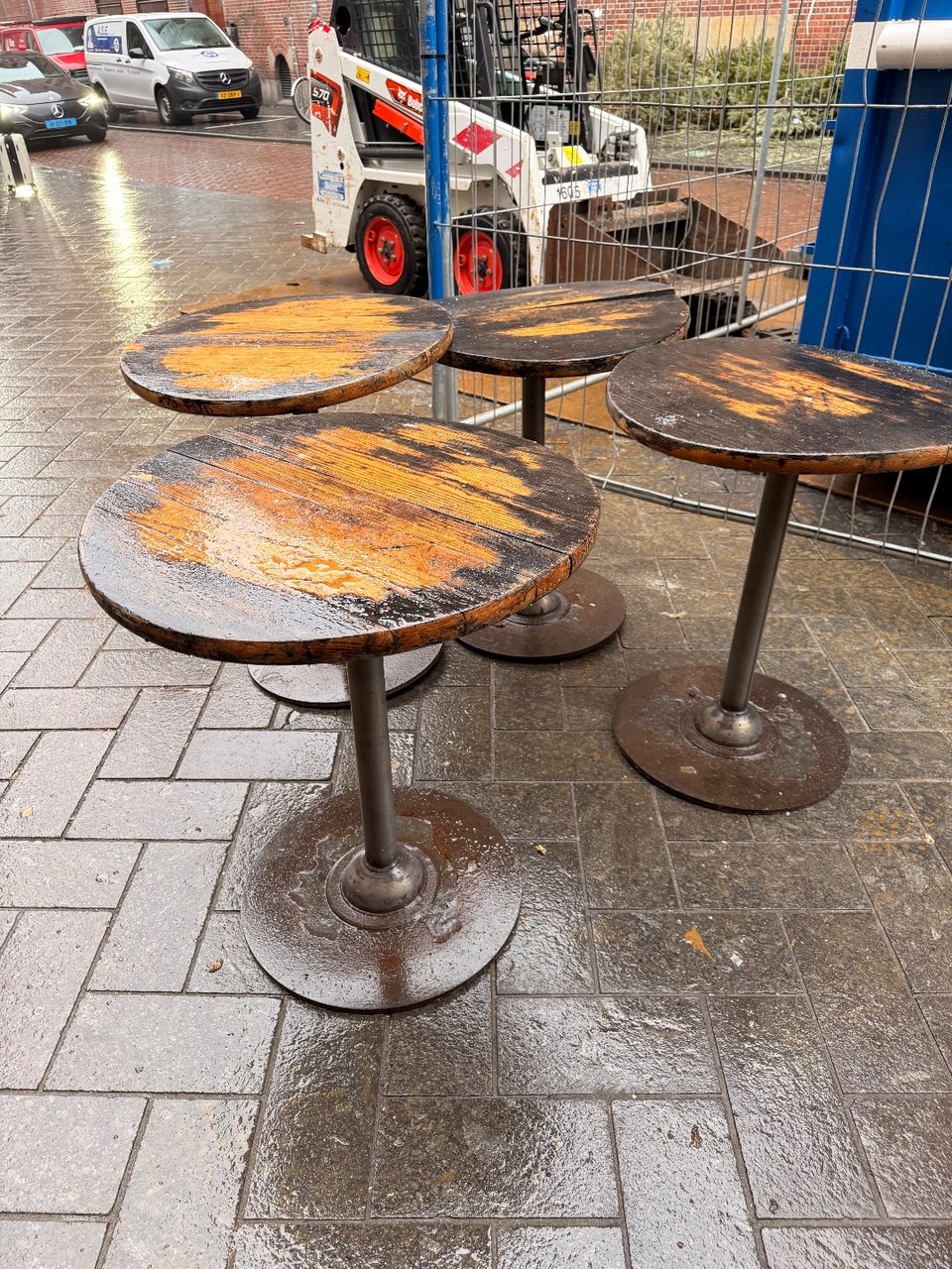 9 ronde terras tafels
Waarvan 2 met kapot houten blad
Tafelpoten nog goed her te gebruiken