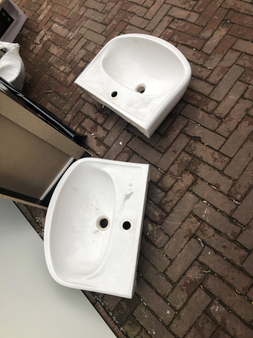 Two wash bassins and a chest of drawer on its side.