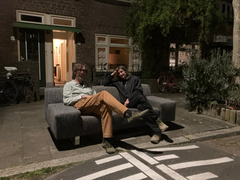 Twee-en-halfzitsbank (195 cm breed) gemêleerde antracietkleurige stof, met brede armleuningen en verchroomd stalen onderstel, met brandplek bij rechterleuning. Aan de straat op Bucheliusstraat 12 in Tuinwijk, Utrecht