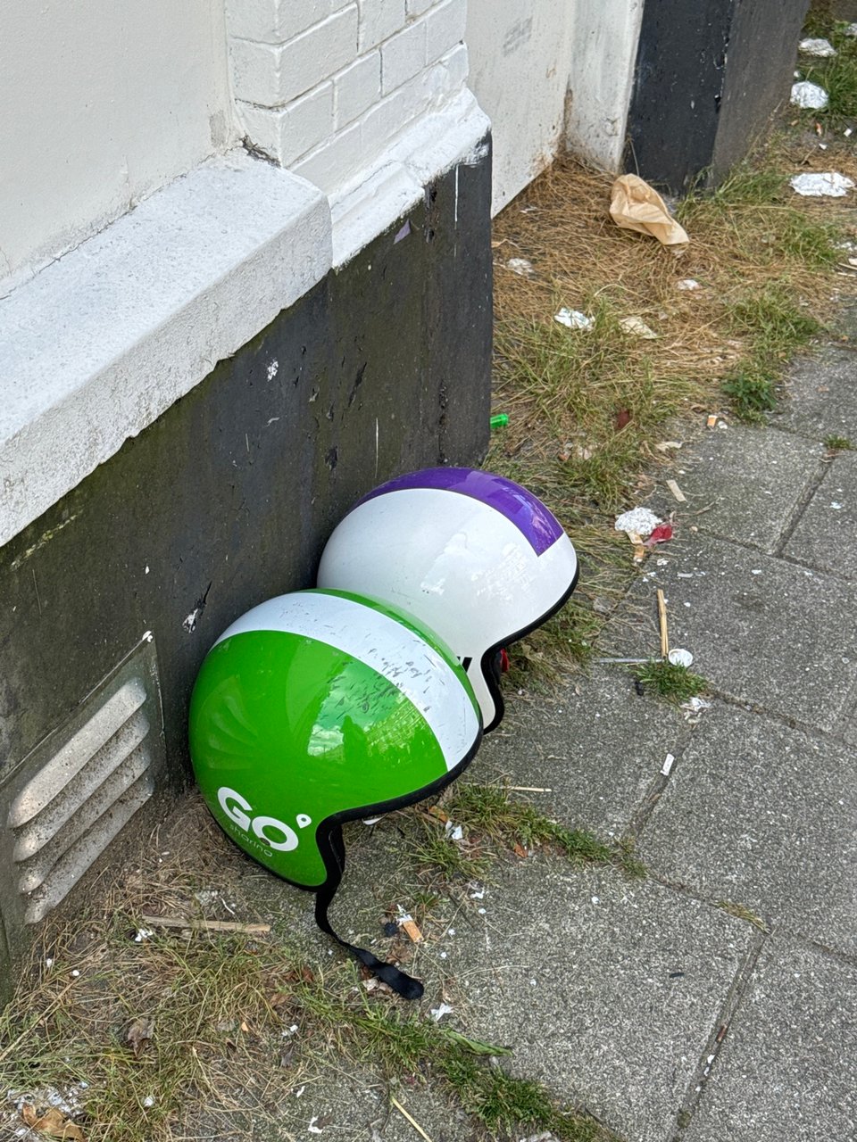 Two helmets that are from ride sharing companies but have been abandoned and saved from the trash