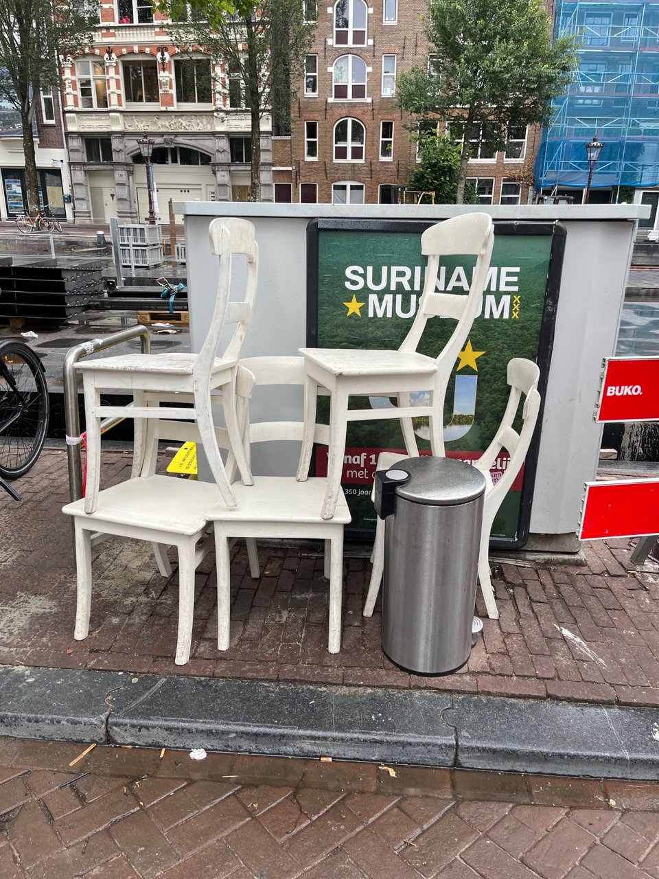 Een kast, vijf witte stoelen en een prullenbak